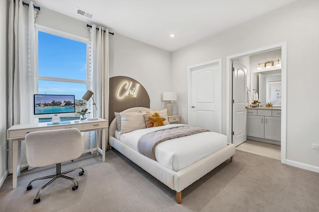 bedroom with connected bathroom and light colored carpet