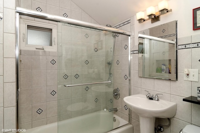 bathroom featuring enclosed tub / shower combo, toilet, vaulted ceiling, and tile walls