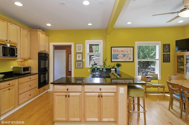 kitchen with a wealth of natural light, black appliances, and light brown cabinets