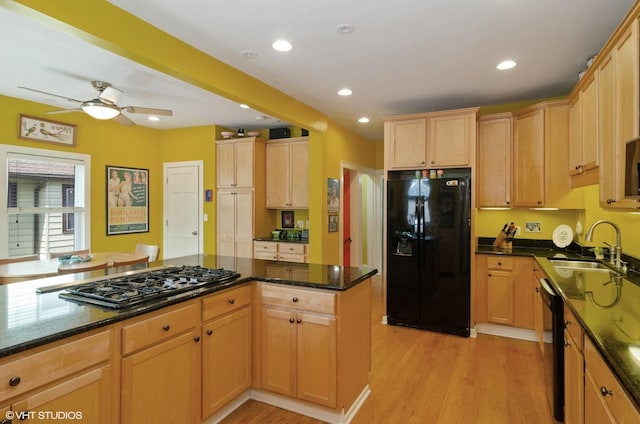 kitchen featuring dark stone counters, sink, light hardwood / wood-style flooring, and black appliances