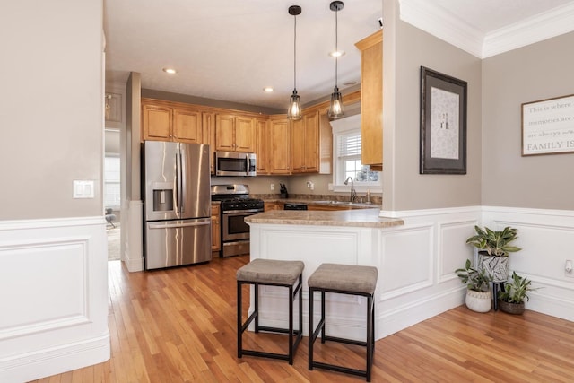 kitchen featuring a kitchen bar, light wood-type flooring, ornamental molding, appliances with stainless steel finishes, and kitchen peninsula