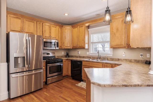 kitchen with sink, hanging light fixtures, light hardwood / wood-style flooring, kitchen peninsula, and stainless steel appliances