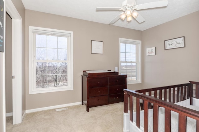 carpeted bedroom with ceiling fan and a crib