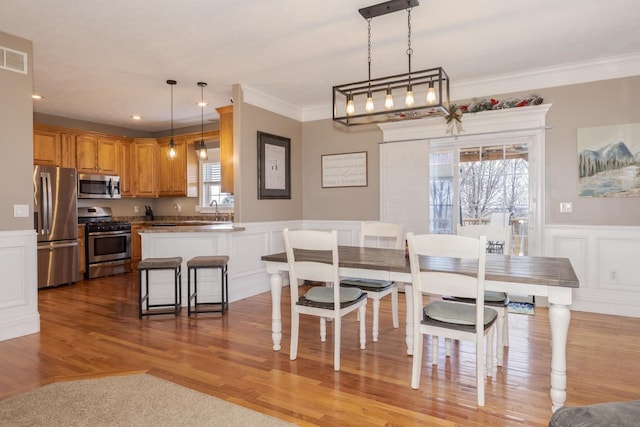 dining area featuring ornamental molding, sink, and light wood-type flooring