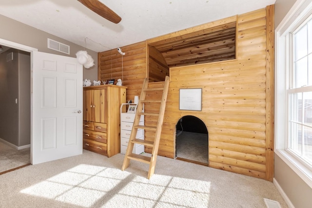 unfurnished bedroom featuring log walls, light carpet, and multiple windows