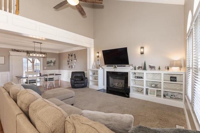 carpeted living room with a high ceiling, ornamental molding, and ceiling fan