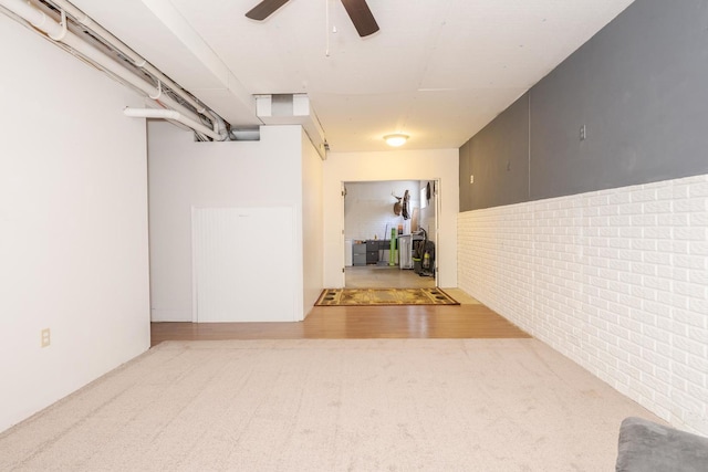 basement with ceiling fan, brick wall, and carpet flooring