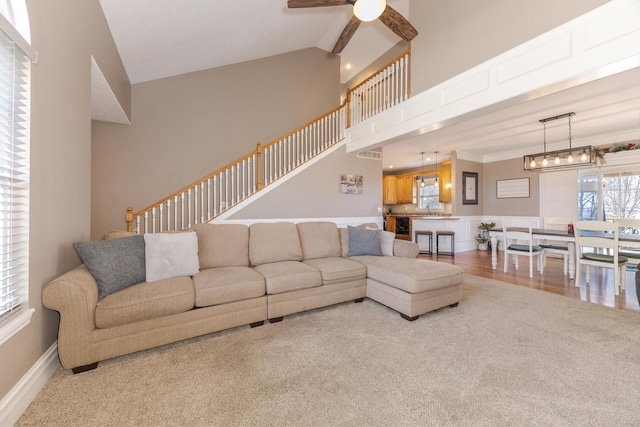 living room with sink, high vaulted ceiling, ornamental molding, hardwood / wood-style flooring, and ceiling fan with notable chandelier