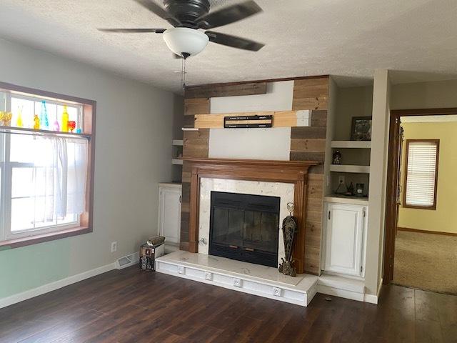 unfurnished living room featuring ceiling fan, dark hardwood / wood-style flooring, and a textured ceiling