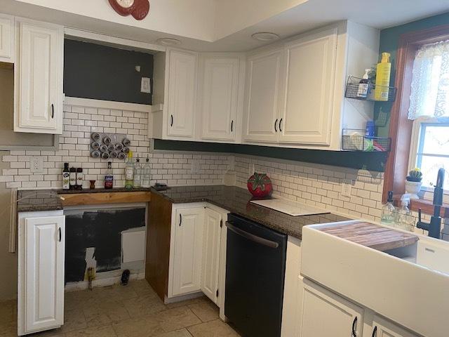 kitchen with a healthy amount of sunlight, white cabinets, decorative backsplash, and black dishwasher