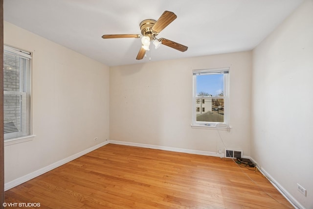 spare room with light wood-type flooring, baseboards, visible vents, and ceiling fan