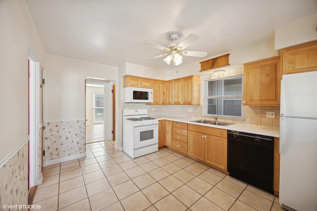 kitchen with a sink, a wainscoted wall, white appliances, and light countertops