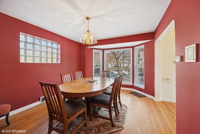 dining area with a notable chandelier, light wood-style floors, and baseboards