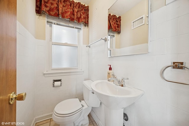 bathroom with visible vents, toilet, and tile walls