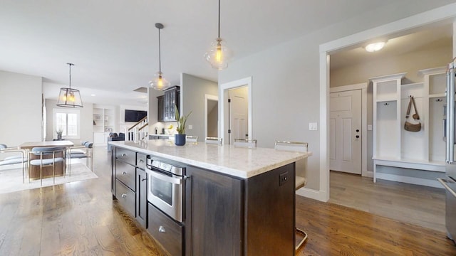 kitchen with hardwood / wood-style flooring, dark brown cabinets, pendant lighting, and a center island