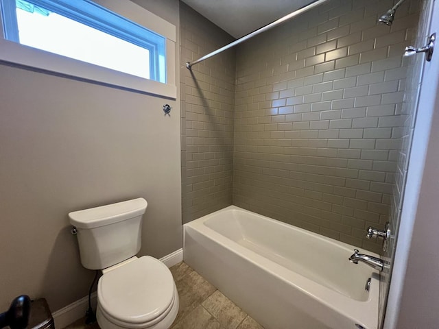 bathroom featuring tile patterned flooring, tiled shower / bath, and toilet