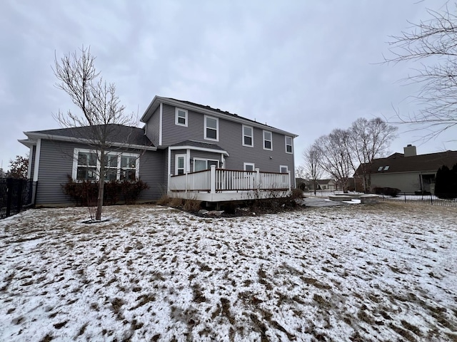 snow covered rear of property with a deck