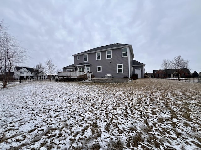 snow covered house featuring a deck and a garage