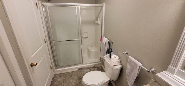 bathroom with toilet and a shower with shower door