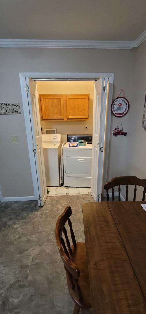 clothes washing area featuring independent washer and dryer, crown molding, and cabinets