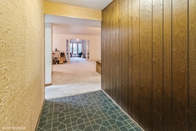 corridor featuring carpet and wood walls