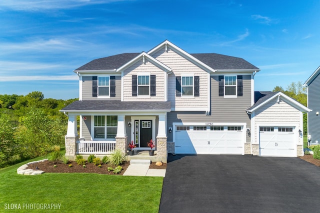 craftsman-style house with a garage, a front yard, and covered porch