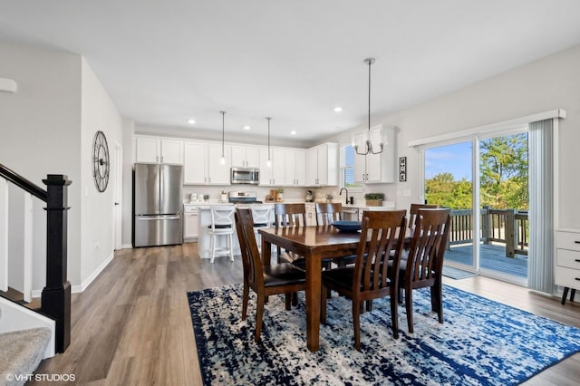 dining room with an inviting chandelier, sink, and light hardwood / wood-style flooring