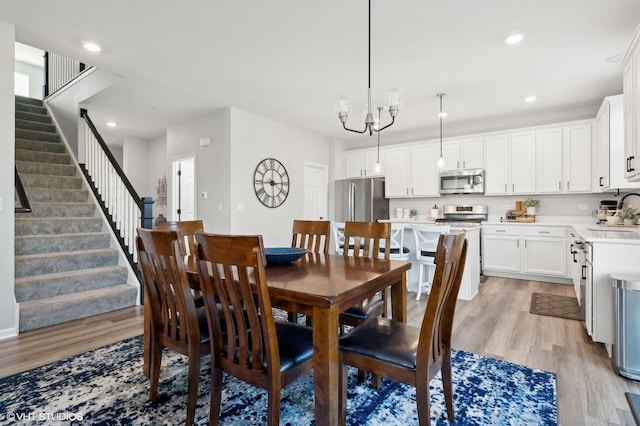 dining space with light hardwood / wood-style floors, sink, and a notable chandelier