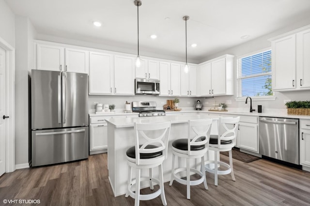 kitchen featuring pendant lighting, stainless steel appliances, a kitchen island, and white cabinets