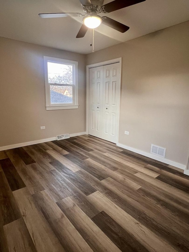 unfurnished bedroom featuring dark wood-type flooring, a closet, and ceiling fan