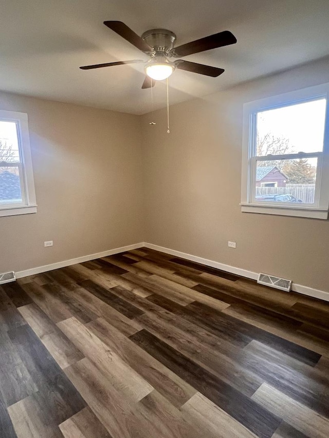 spare room with dark wood-type flooring, ceiling fan, and a wealth of natural light