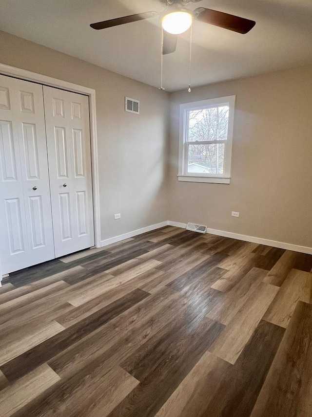 unfurnished bedroom with dark wood-type flooring, ceiling fan, and a closet