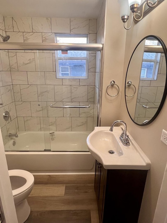 full bathroom with vanity, hardwood / wood-style floors, toilet, and combined bath / shower with glass door