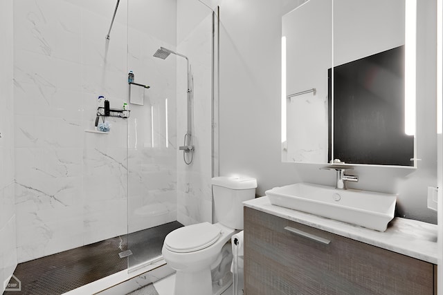 bathroom with vanity, toilet, and a tile shower