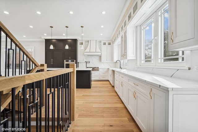 kitchen featuring appliances with stainless steel finishes, decorative light fixtures, white cabinetry, custom exhaust hood, and a center island