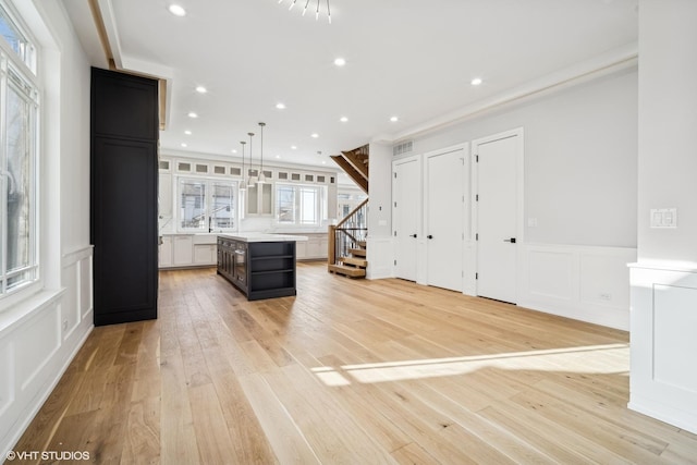 kitchen with hanging light fixtures, white cabinetry, a center island, and light hardwood / wood-style floors