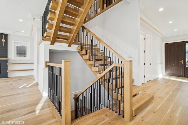 stairway with wood-type flooring and ornamental molding