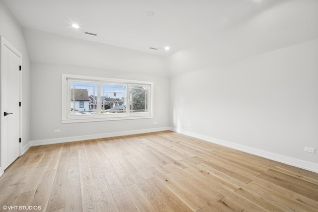 spare room featuring light hardwood / wood-style flooring and vaulted ceiling