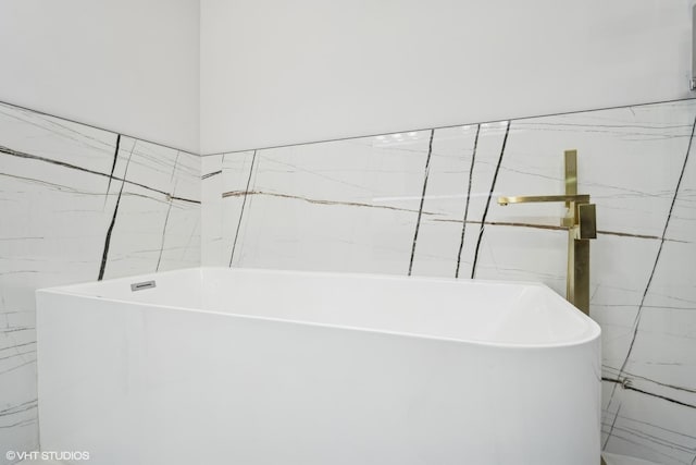 bathroom featuring tile walls and a bath