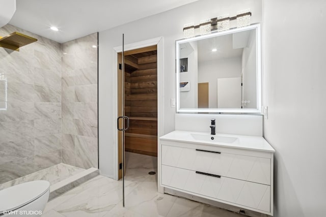 bathroom with vanity, tiled shower, and toilet