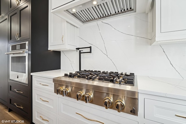 kitchen featuring stainless steel appliances, custom range hood, and white cabinets