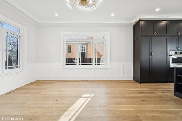 unfurnished dining area with ornamental molding and light hardwood / wood-style floors