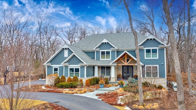 craftsman inspired home with roof with shingles and stone siding