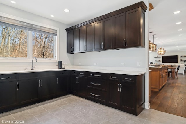 kitchen featuring a sink, recessed lighting, hanging light fixtures, light countertops, and dark brown cabinetry