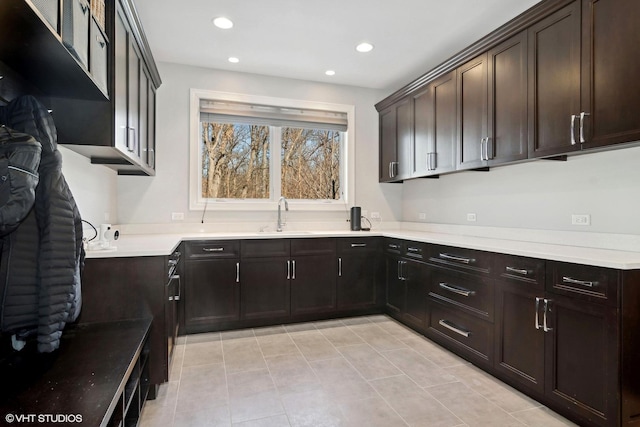 kitchen featuring dark brown cabinetry, light countertops, a sink, and recessed lighting