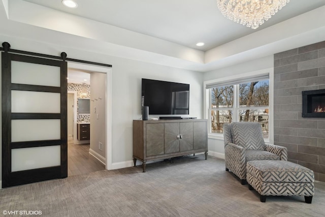 living area with carpet floors, a barn door, and baseboards