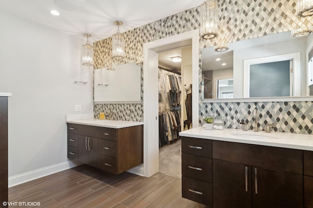 full bathroom with a sink, decorative backsplash, two vanities, and a spacious closet