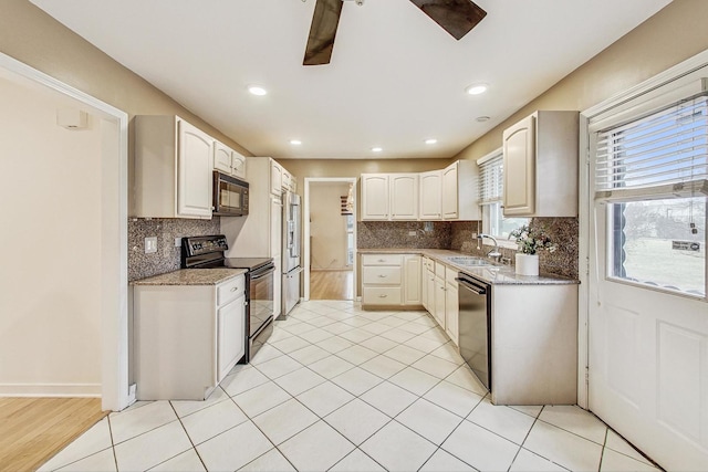 kitchen with sink, light tile patterned floors, tasteful backsplash, black appliances, and light stone countertops