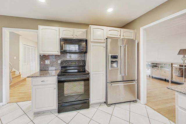 kitchen with white cabinetry, light stone countertops, backsplash, and black appliances