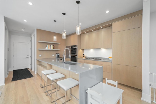 1834 N Rockwell St Unit 1R, Chicago, IL 60647 - kitchen featuring a sink, modern cabinets, light brown cabinetry, light wood-style flooring, and a kitchen breakfast bar